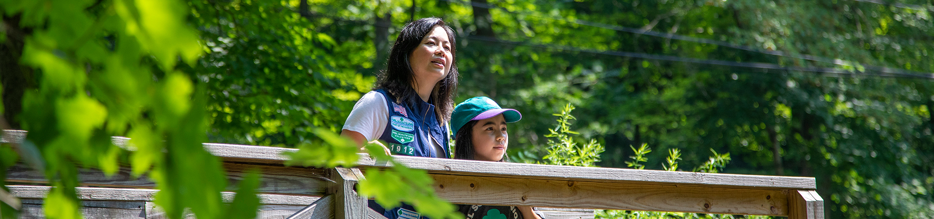  girl scout volunteer parent with young girl hiking outside at state park 