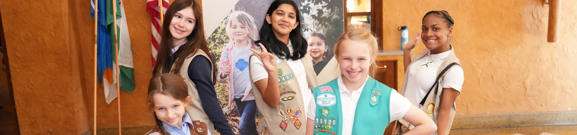  portrait of ambassador girl scout wearing vest and smiling at camera in front of a brick building 